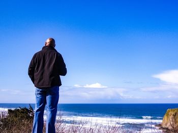 Rear view of man looking at sea against sky