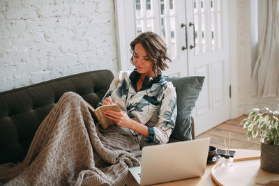 Smiling young brunette woman working remotely from cozy home