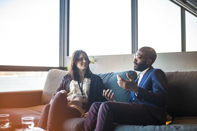 Businessman talking to businesswoman while sitting in office