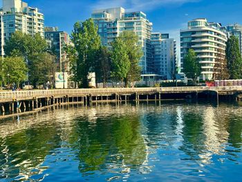 Bridge over river by buildings in city against sky