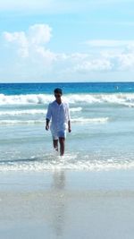 Full length of man standing on beach against sky