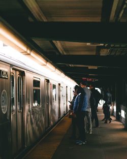 Side view of passengers standing by metro train at subway station