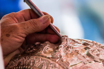 Cropped hand of artist carving metal in workshop