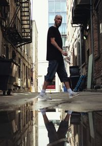 Side view of man standing by buildings in city