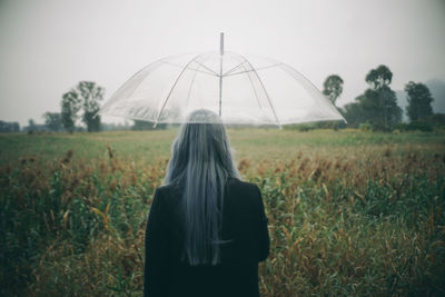 Rear view of woman standing on field against sky