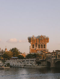 Buildings by river against clear sky