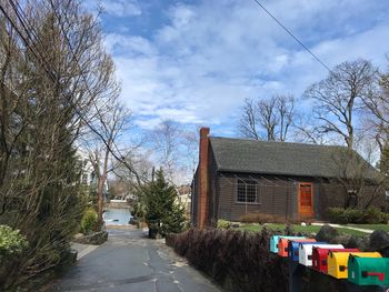 Road amidst trees and buildings against sky