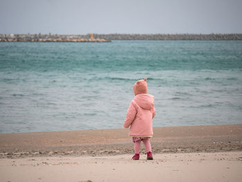 Rear view of woman standing at beach