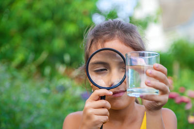 Girl looking at water through magnifying glass