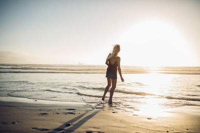 Woman walking on beach against clear sky