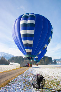 Scenic view of hot air balloon on field against sky