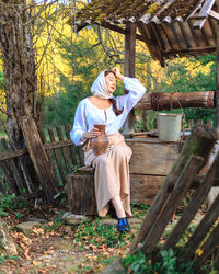 Side view of young woman sitting on bench