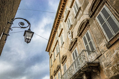 Low angle view of street light by building against sky