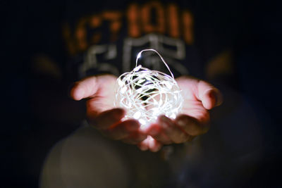 Midsection of person holding illuminated string lights