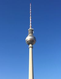 Low angle view of communications tower against blue sky