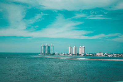 Sea by buildings against blue sky