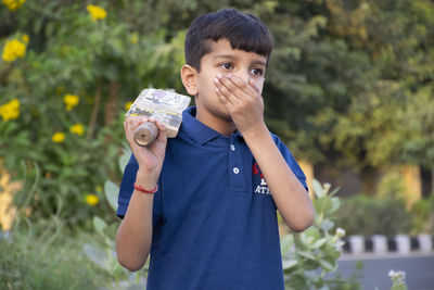 Portrait of boy holding bat coughing