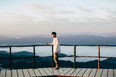 Full length of man standing on railing against mountain