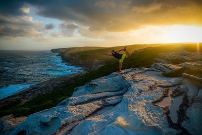 Scenic view of man standing on rocks next to sea