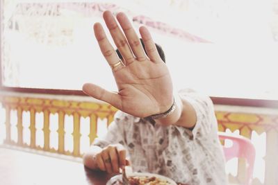 Close-up of man gesturing stop sign while having food at restaurant