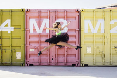 Ballet dancer dancing against cargo containers