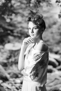 Side view of young woman standing against trees