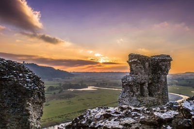 Rock formations on landscape against sky during sunset