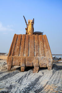 Old rusty metallic structure on beach against sky