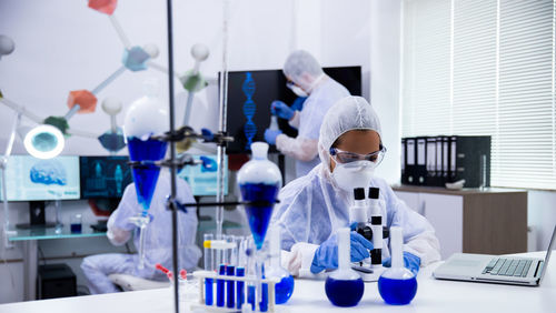 Scientist doing research colleague in background at laboratory