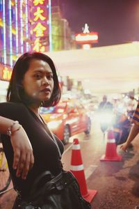 Portrait of woman standing in city at night