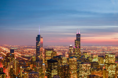 Illuminated cityscape against sky at dusk