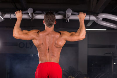 Rear view of shirtless man using mobile phone