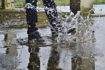 Low section of man splashing puddle water