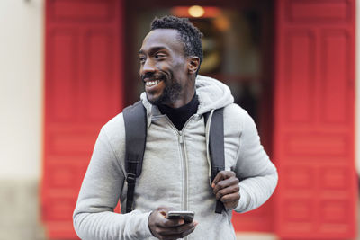 Man using with backpack using mobile phone while standing outdoors