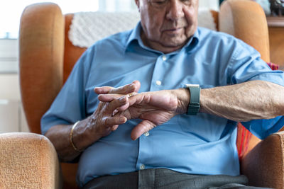 Elderly man wearing a smart emergency alarm bracelet around wrist at home