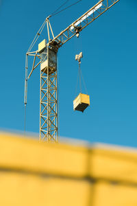 Low angle view of crane against clear blue sky