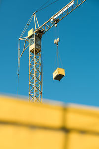 Low angle view of crane against clear blue sky