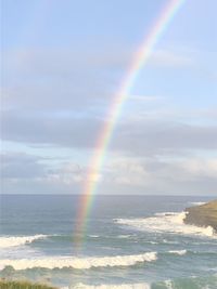 Scenic view of rainbow over sea against sky