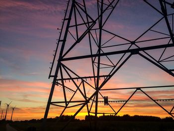 Low angle view of silhouette electricity pylon against sky during sunset