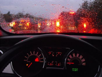 Illuminated road seen through wet windshield of car