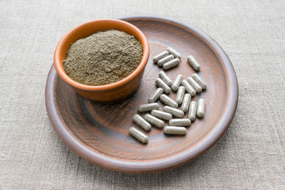 Triphala capsules and powder on clay plate. triphala is polyherbal ayurvedic medicine