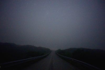 Road amidst fog against sky at night