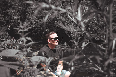 Portrait of young man standing against trees