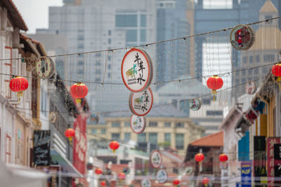 Lanterns hanging on street against buildings in city