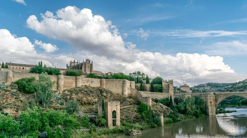 Arch bridge over river against cloudy sky