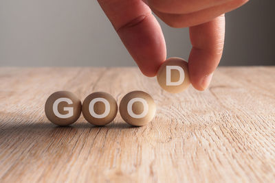 Cropped hand arranging balls with good text on wooden table