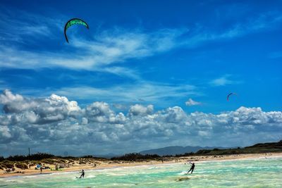People flying over sea against sky