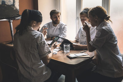 Male and female chefs discussing at table in restaurant