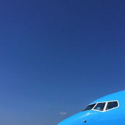 Low angle view of airplane wing against clear blue sky