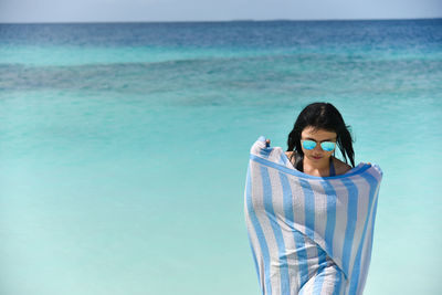 Young woman standing in sea against sky